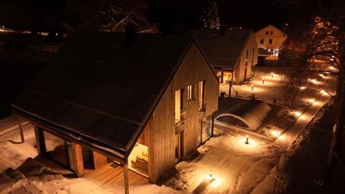 切尔尼杜尔Rezidence Za Vodou - Vážka的一座晚上在雪中点亮的建筑