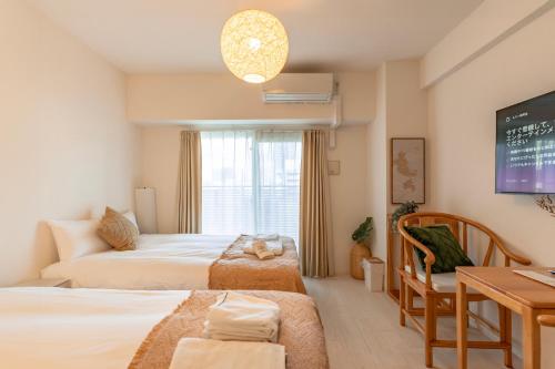 大阪谷町君ホテル　難波80的一间卧室配有两张床、一张桌子和一台电视。