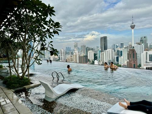 吉隆坡Axon Residence By Luxury Suites的一座建筑物屋顶上的游泳池,里面的人