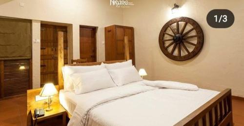 戈尔哈布尔Nisarg Resort的一间卧室配有一张大床,墙上挂着一个时钟