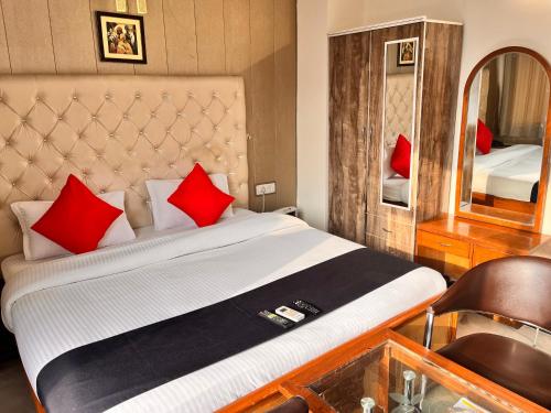 古尔冈Hotel Gracious的一间卧室配有一张带红色枕头和镜子的床