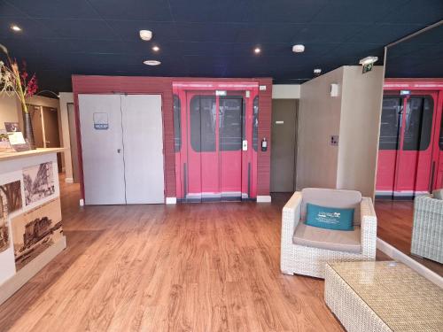 拉加尔德Kyriad Toulon Est Hyeres La Garde的一间设有粉红色门、一张沙发和椅子的房间