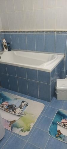 皮罗特Apartman Gaga的蓝色瓷砖浴室设有浴缸和地板上的垫子。