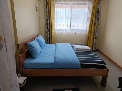 卡巴莱Bunyonyi Lakefront Leisure Lodge的一间卧室配有一张带蓝色床单的床和一扇窗户。