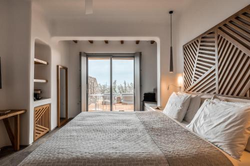 萨鲁Alissachni Mykonos的一间卧室配有一张大床和大型木制床头板