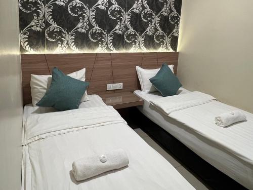 关丹KUANTAN BESERAH BUDGET HOTEL的配有白色和蓝色枕头的酒店客房的两张床