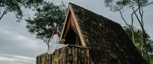 PujunganKAMPUNG KOPI CAMP的坐在树屋窗户上的女人