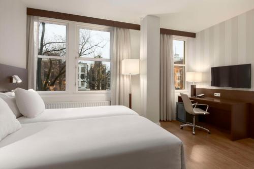 阿姆斯特丹阿姆斯特丹市中心NH酒店的酒店客房设有一张床、一张书桌和窗户。