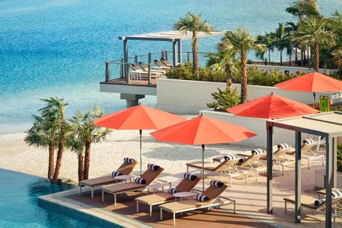 阿布扎比Grand Hyatt Abu Dhabi Hotel & Residences Emirates Pearl的毗邻大海的带椅子和遮阳伞的游泳池