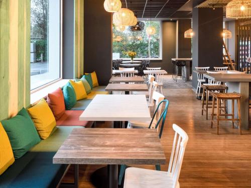 布列登ibis Styles Bredene的餐厅设有木桌和五颜六色的椅子