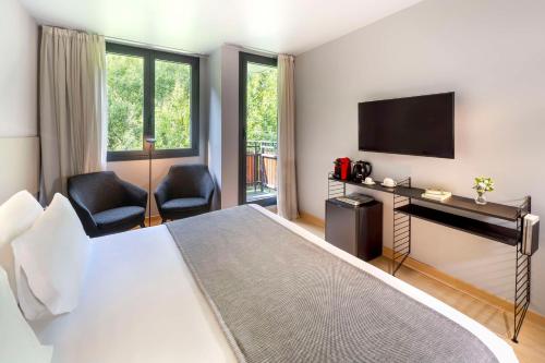 马萨纳NH Collection Andorra Palomé的配有一张床和一台平面电视的酒店客房