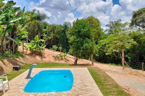 圣罗克Chácara prox Rota do Vinho com piscina, churrasqueira, área verde, animaizinhos e muito sossego的一座绿树成荫的庭院中的蓝色游泳池