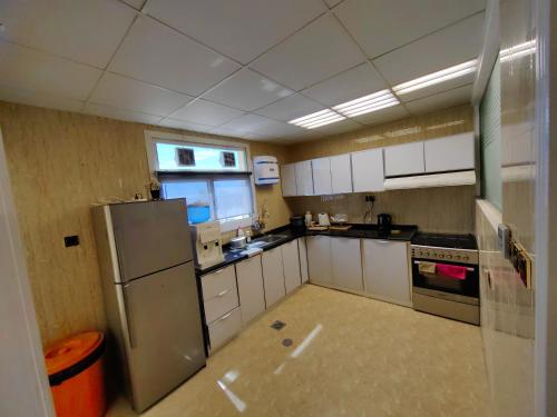 塞拉莱الشقة البحرية الدهاريز的厨房配有白色橱柜和不锈钢冰箱