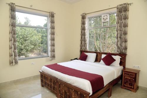 萨瓦伊马多普尔Ranthambhore Tiger Niwas的一间卧室设有一张大床和两个窗户。