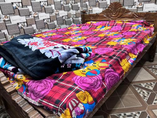 德奥加尔Sunrise Plaza ( ठहरने का उत्तम प्रबंध)的床上有五颜六色的被子