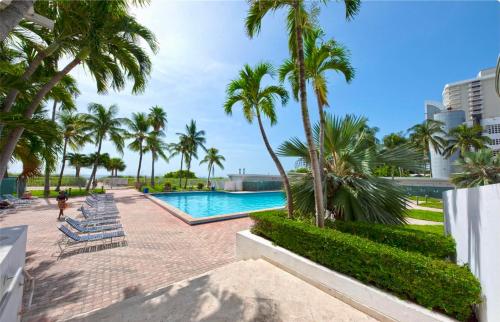 迈阿密海滩Directly on the Beach with Pool & Ocean View的一个带棕榈树和躺椅的游泳池