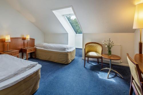 奥尔堡Hotel Scheelsminde的酒店客房,配有两张床、一张桌子和一把椅子