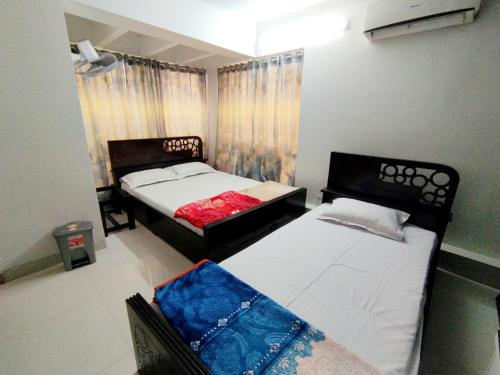 达卡Hotel Labbaik Dhanmondi的一间卧室设有两张床和窗户。