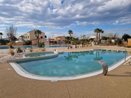 塞里尼昂Super mobil-home aux Sables du Midi的棕榈树度假村内的大型游泳池