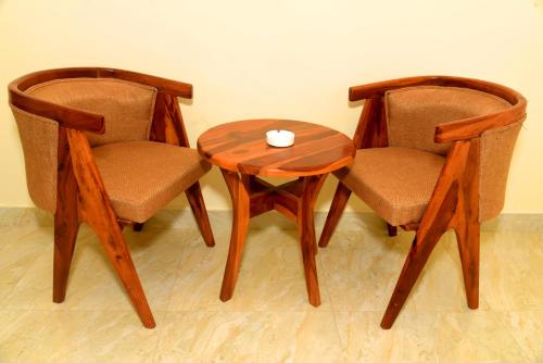 萨瓦伊马多普尔Ranthambhore Tiger Niwas的两张椅子和一张木桌,上面有杯子