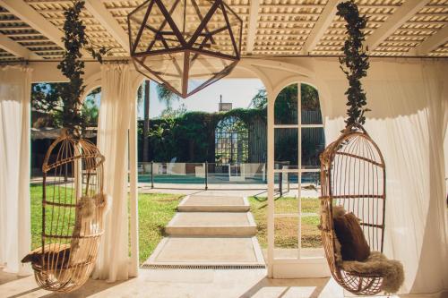 科尔多瓦Casa Onas Hotel Boutique Córdoba的门廊设有两把悬挂秋千椅和一个花园