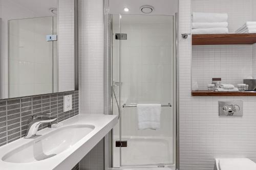 伦敦伦敦塔希尔顿逸林酒店的白色的浴室设有水槽和淋浴。