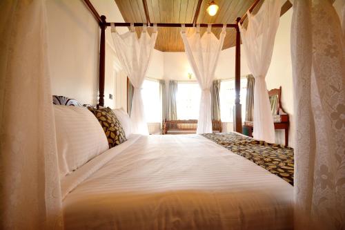 科代卡纳尔Craigmore By Kodai Resort Hotel的卧室配有带白色窗帘的天蓬床