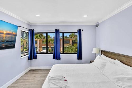 劳德代尔堡Las Olas Luxury 2BR Apt Pool的一间卧室配有床和蓝色窗帘的窗户