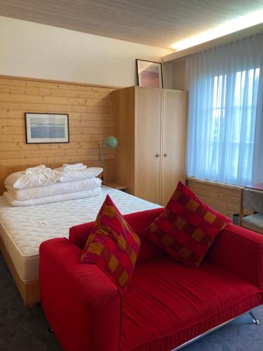 斯派克FriendsHouse Appenzellerhof的一间卧室配有一张床和一张红色的沙发