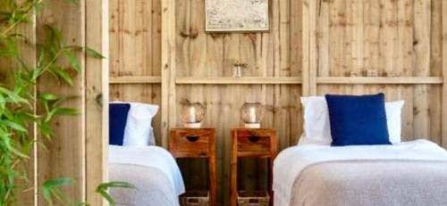 托波因特Tregantle Farm Eco GLAMPSITE的木墙客房中的两张床和蓝色枕头