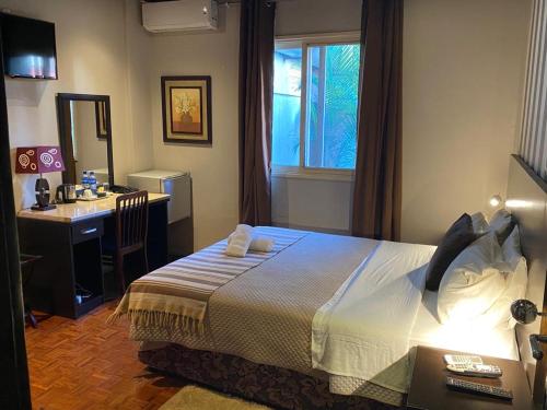 马普托HOTEL RESIDENCIAL CITY的一间卧室配有一张床、一张书桌和一个窗户。