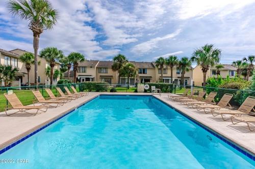 巴拿马城海滩Gulf Highlands Sea的公寓前方的游泳池设有椅子和棕榈树