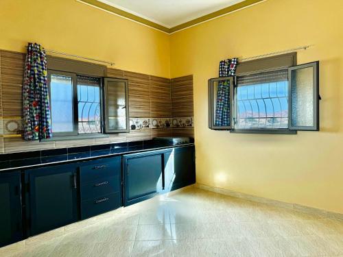 梅尔祖卡Merzouga DesertView Apartment的一间设有蓝色橱柜和两个窗户的厨房