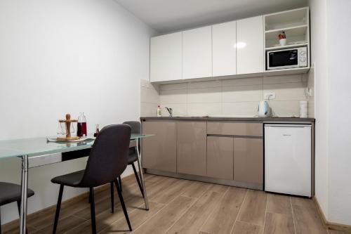 EminovciCherry Berry Apartmani的厨房配有白色橱柜和桌椅