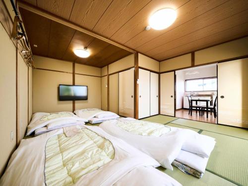 大垣Okasan Hotel - Vacation STAY 66120v的客房设有三张床,墙上配有电视。