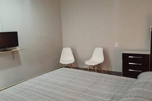 塔里哈Casa Magnolia的一间卧室配有一张床和两把白色椅子