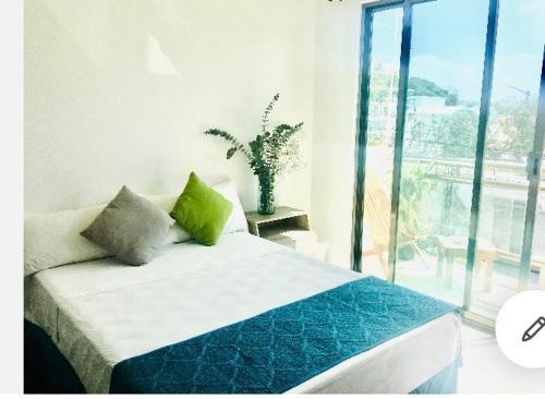 普拉亚卡门Casa Ohana By Utopia的一间卧室配有一张带绿色枕头的床和一扇窗户