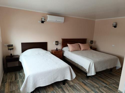 卡尔德拉Cafetto Hostal的一间卧室配有两张带白色床单的床