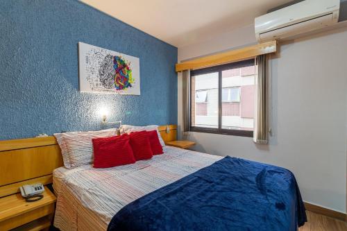 圣保罗LFlats no Hotel Hampton Park Jardim Paulista的一间卧室配有一张带红色枕头的床和一扇窗户