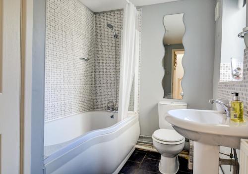 SalhouseThe Old Post Room的浴室配有白色浴缸、盥洗盆和卫生间。