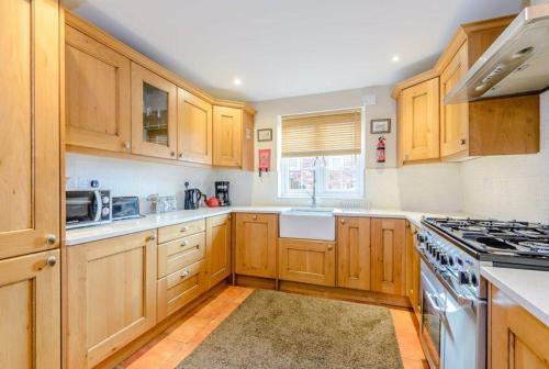 塔博雷Tarporley Holiday Cottage的厨房配有木制橱柜和炉灶烤箱。