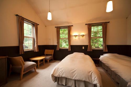 松本诗意酒店的一间卧室设有两张床、一把椅子和窗户。
