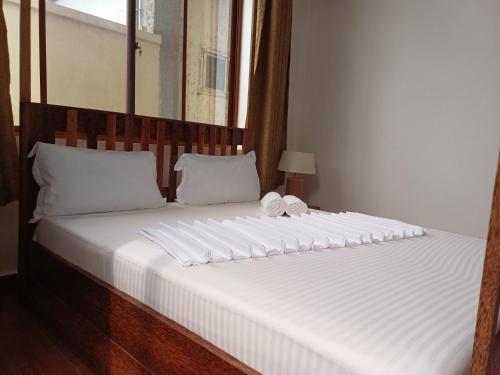 南威Jodari Hotel Nungwi的一张白色大床,配有木制床头板和白色枕头