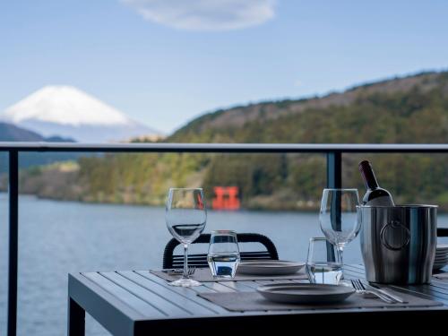元箱根Rakuten STAY FUJIMI TERRACE 箱根芦ノ湖　的一张桌子,上面有眼镜和一瓶葡萄酒
