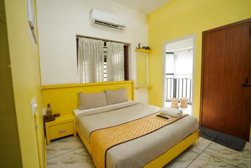 科泽科德Twinn Waves Calicut的黄色间内一间卧室,配有一张床