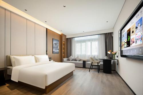 惠州惠州惠阳新都会亚朵酒店的酒店客房设有一张白色大床和一张沙发。