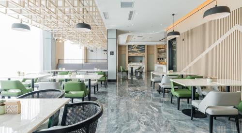 昆明昆明大商汇亚朵酒店的餐厅设有白色的桌子和绿色的椅子
