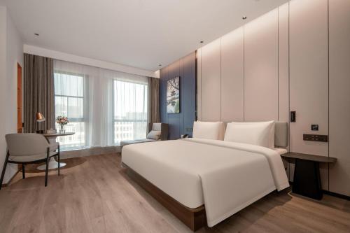杭州杭州火车东站东广场亚朵酒店的卧室配有一张白色大床和一张书桌