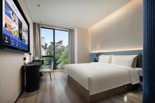 广州广州琶洲会展广州塔地铁站轻居酒店的卧室配有一张白色大床和一台平面电视。