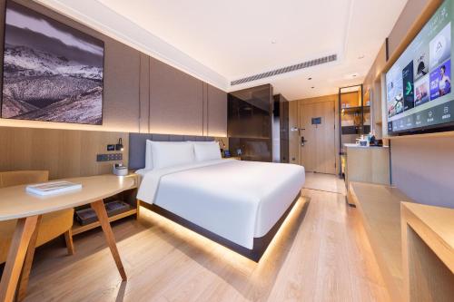 北京北京马家堡地铁站亚朵X酒店的一间卧室配有一张床、一张书桌和一台电视。